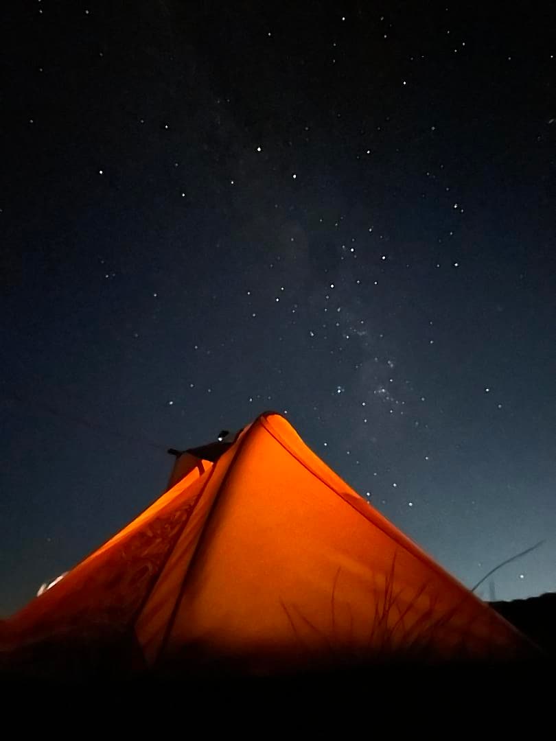 Barraca iluminada por dentro sob um céu cheio de estrelas